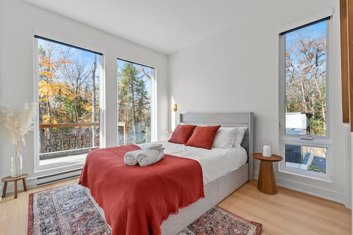 Main bedroom with queen bed, memory mattress, and large windows overlooking the forest.
