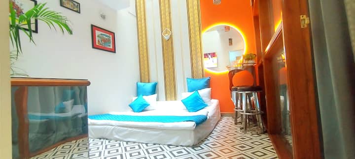 This is a living room just outside bedroom 3. Well ventilated and air conditioning from bedroom but open air on top. Can  be used for sleeping with 6ft by 6ft sofa cum bed and also lounging or watching TV as it has a TV as well.