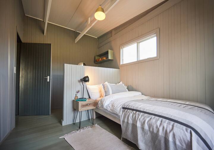 Një krevat i vetëm me tavolinë pranë krevatit dhe abazhur. Ndërtuar në dollap.