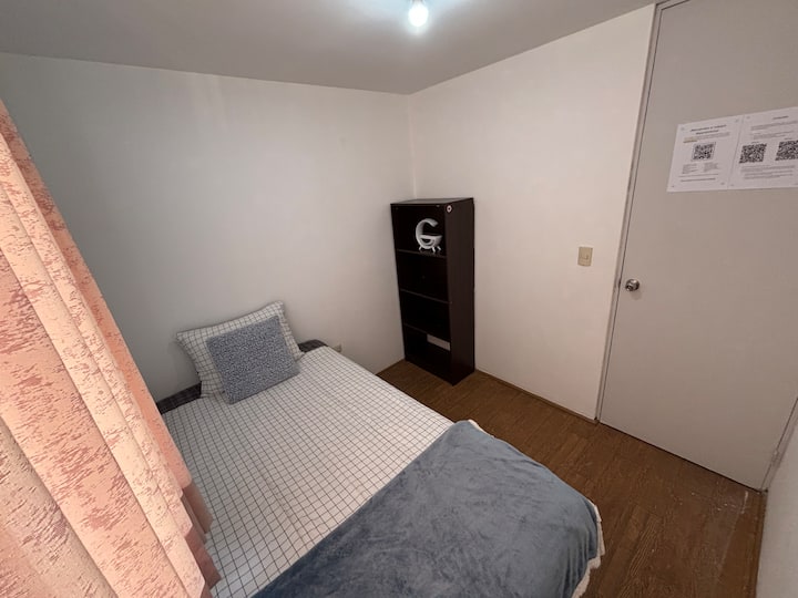 El dormitorio secundario ofrece una cama de plaza y media con ropa a medida y armario.