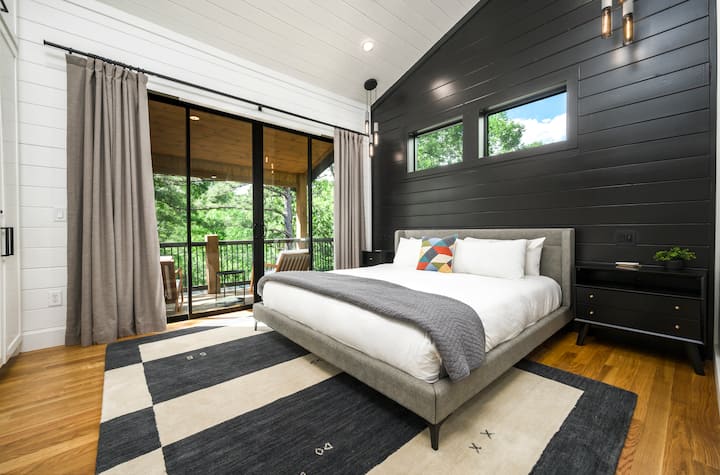 Serene modern bedroom at “Hillside Hideaway” with a cozy bed, stylish decor, and stunning green views for ultimate relaxation.