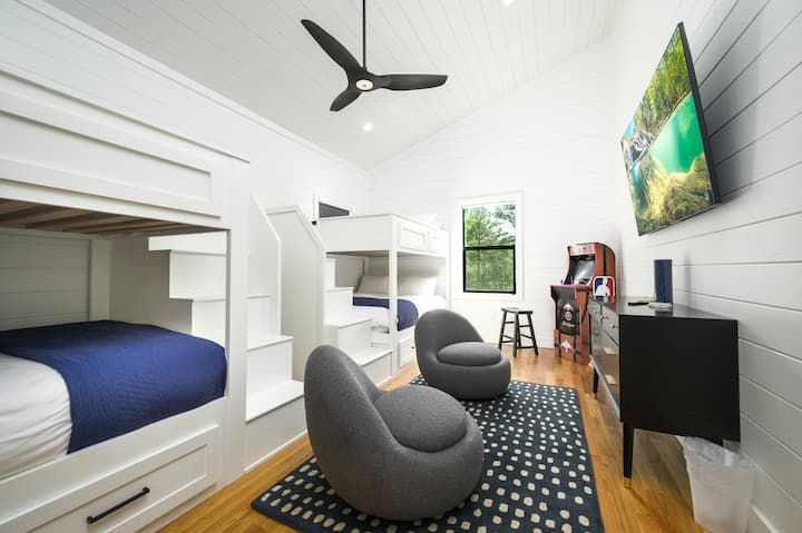 Vibrant kids' room with bunk beds, cozy bean bags, TV, and arcade game—perfect for family fun.