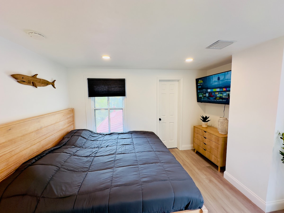 Serene primary bedroom with king‑size bed, wood frame and luxe linens; dresser and closet offer plenty of storage