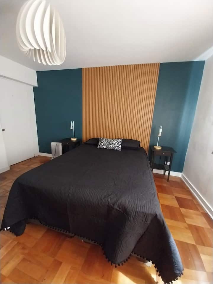 ห้องนอนหลักพร้อมเตียงขนาดควีนไซส์เทียนในสนามเด็กเล่นพนักพิงแผงและพื้นปาร์เก้ มีตู้เสื้อผ้าขนาดใหญ่โต๊ะทำงานขนาดเล็กและเก้าอี้นวม มีหน้าต่างเทอร์โมแพนม่านม้วนและเครื่องทำความร้อนไฟฟ้า