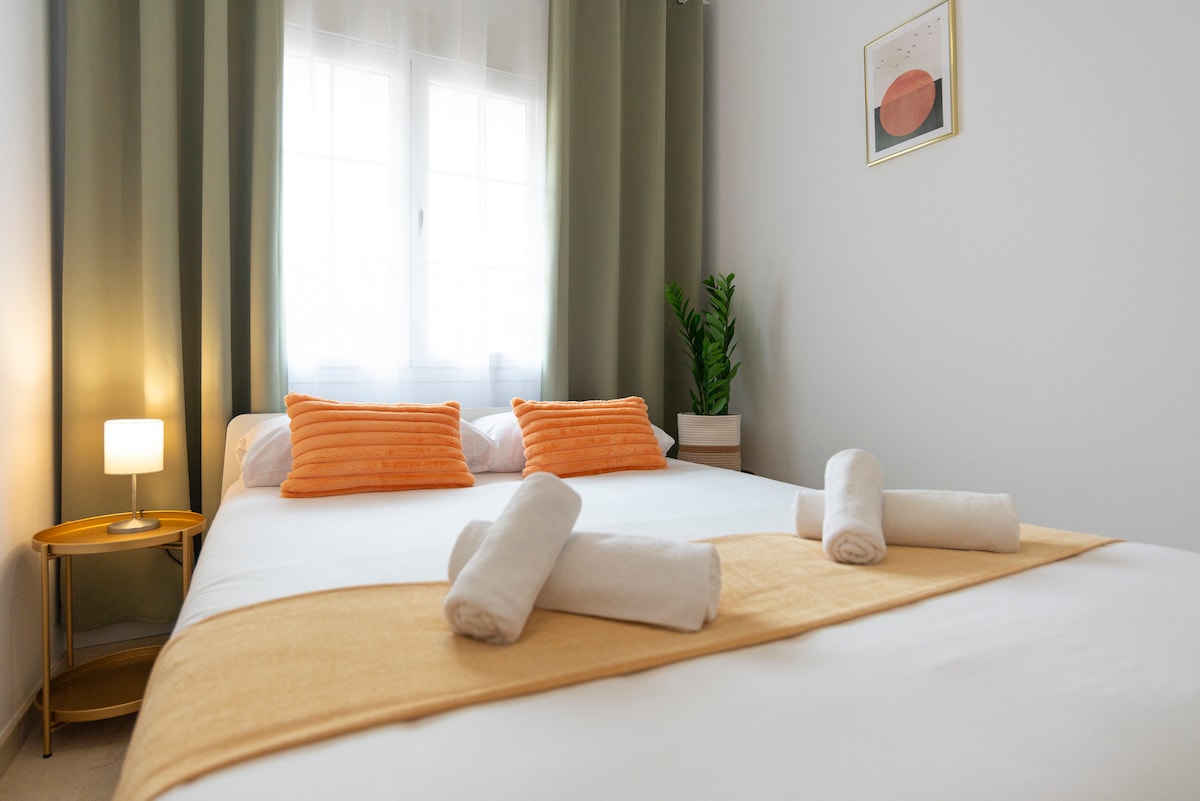 Lichte en vrolijke slaapkamer met een tweepersoonsbed (135 cm), zacht beddengoed en levendige oranje accenten. Beschikt over grote ramen, verduisteringsgordijnen en een gezellige, rustgevende sfeer.