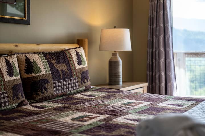 تمدد على سرير خشبي مصنوع يدويًا محاطًا بإطلالات جبلية خلف النافذة مباشرة. مع الإضاءة الناعمة واللمسات الغنية للمقصورة، تبدو هذه الغرفة أرضية ومريحة.