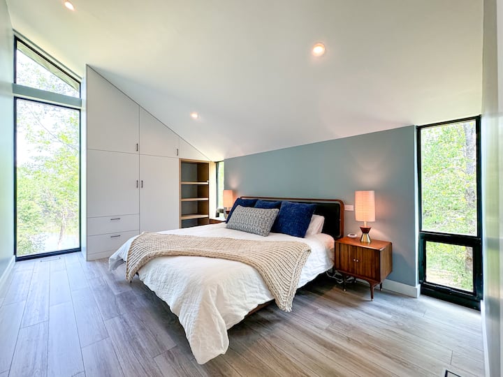 Serene second-floor bedroom with large windows offering beautiful natural views. This room features a king-sized bed and ample closet space, creating a peaceful retreat. Please note, there is no TV in this room.