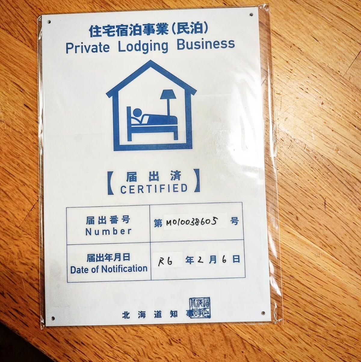 A certification plaque is displayed, indicating that the private lodging business is officially certified. The plaque includes a logo of a bed with a person resting, along with relevant registration number and date information clearly printed.