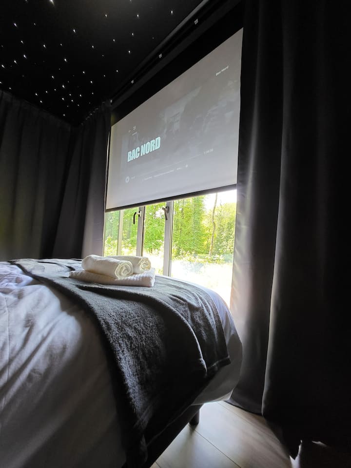 Vychutnajte si veľkú obrazovku priamo oproti posteli:
Náš stropný projektor vám poskytuje prístup k účtu Netflix a prémiovému YouTube pre nezabudnuteľné filmové večery.