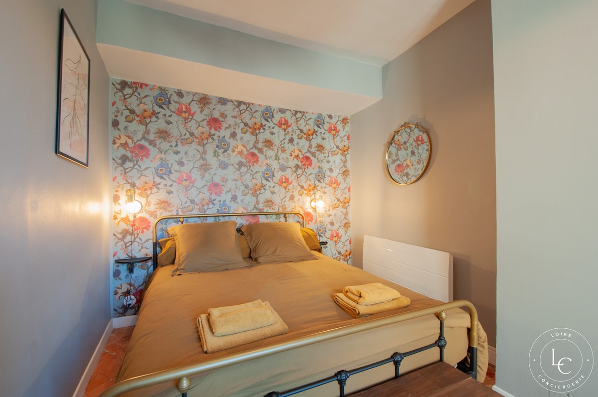Chambre cosy avec lit queen size, décorée d'un papier peint floral. Ambiance apaisante grâce aux couleurs douces et éclairages d'appoint. Un banc en bois au pied du lit ajoute une touche rustique. Dispose aussi d'un rangement pour vos affaires.
