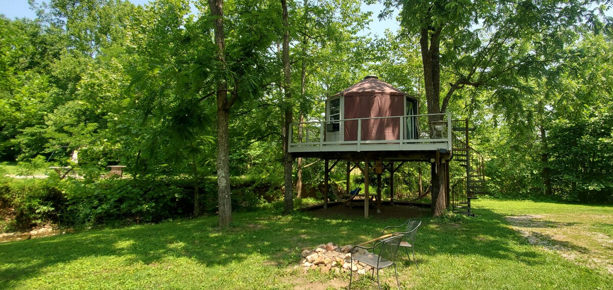 Underneath is a picnic table, 2 hammocks, and nearby firepit. Outhouse is to the right of this photo.