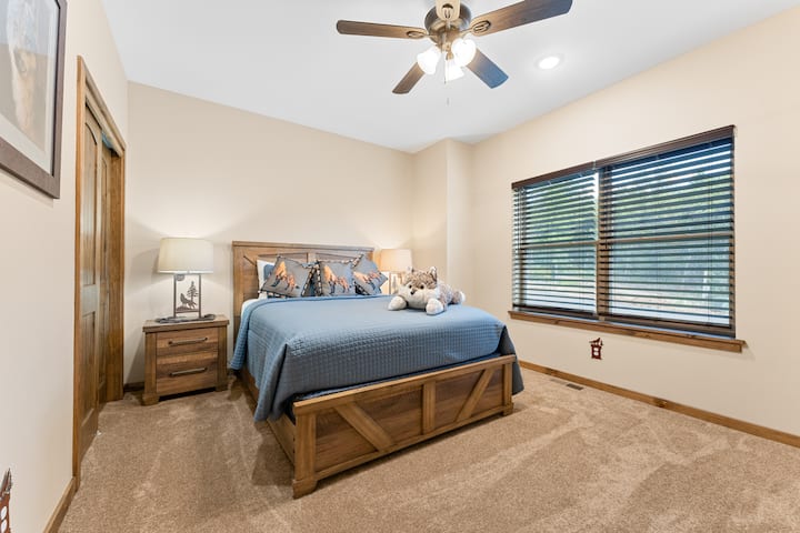 Slaapkamer op de begane grond met queensize bed en een aangrenzende badkamer.