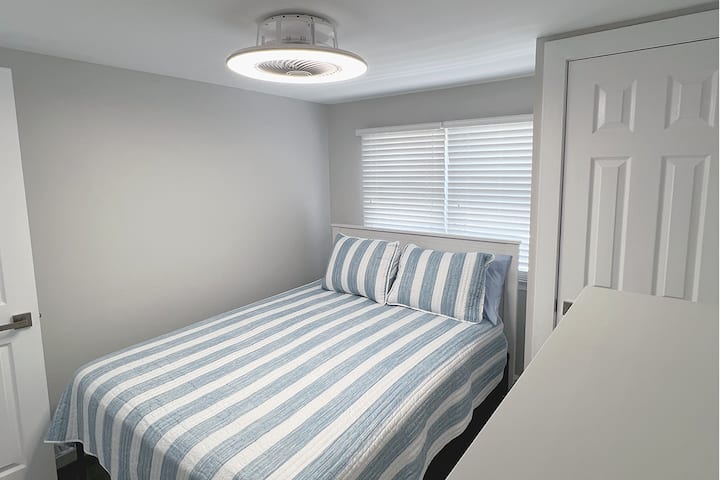 The 2nd bedroom or middle bedroom of this family vacation rental features a queen bed, dresser, linens, closet and shelf rack for personal items. The bed is high enough to slide your suitcases underneath for easy storage. 