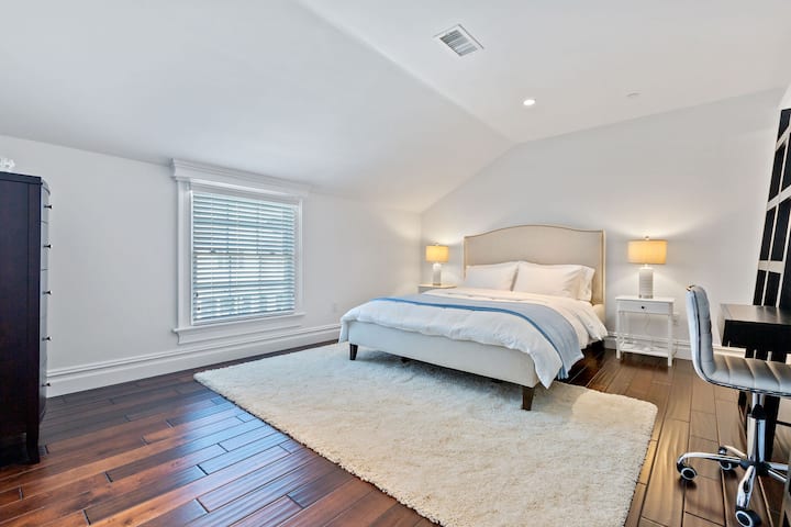 Spacious bedroom with queen size bed, dresser, closet, dedicated workspace and ensuite bathroom. 