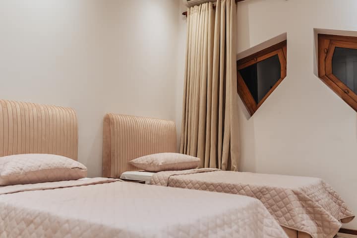 Соба 3 е мирна спална соба со два единечни кревета, секој украсен со розови јоргани и перници. Креветите имаат високи, перничиња на главата во светлобеж боја. 