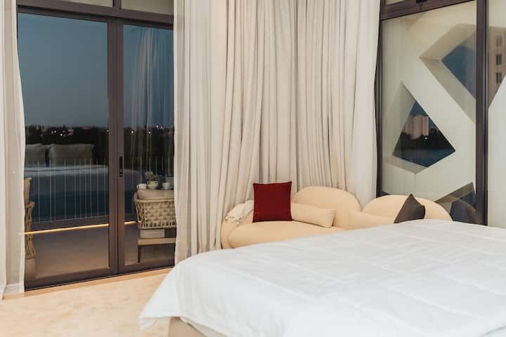 Искусете го спокојството во оваа елегантна спална соба со прозорци од подот до таванот покриени со луксузни завеси што течат.