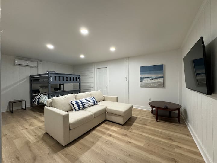 เตียงสองชั้นเต็มรูปแบบโซฟาขนาดใหญ่สมาร์ททีวีขนาดใหญ่ นี่เป็นห้องชั้นล่างที่มีประตูไปยังพื้นที่หลักชั้นบน 