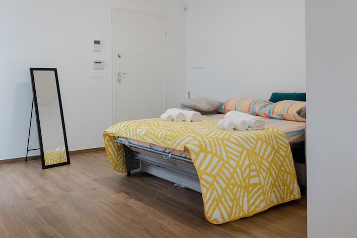 Fleti ya kifahari yenye sebule iliyosafishwa: kitanda kikubwa cha sofa kinachofaa kwa ajili ya mapumziko na kioo kinachoongeza mwangaza na kutoa kina kwa mazingira.