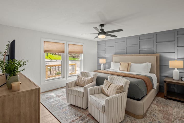King size bedroom with two swivel chairs, tv, and an ensuite bathroom. 