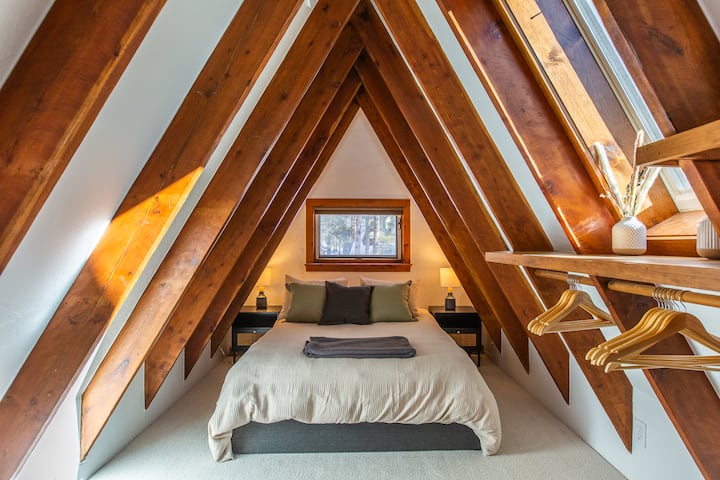 غرفة نوم علوية واسعة مع إضاءة طبيعية وأجواء مريحة. يحتوي السرير على أدراج يمكن استخدامها للتخزين الإضافي، بالإضافة إلى الشماعات ورفوف الأمتعة. 