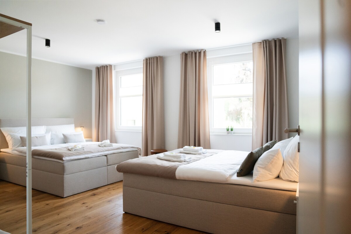 Un dormitorio inundado de luz con dos amplias camas dobles y una cómoda zona de trabajo. Dos ventanas garantizan la luminosidad y la frescura.