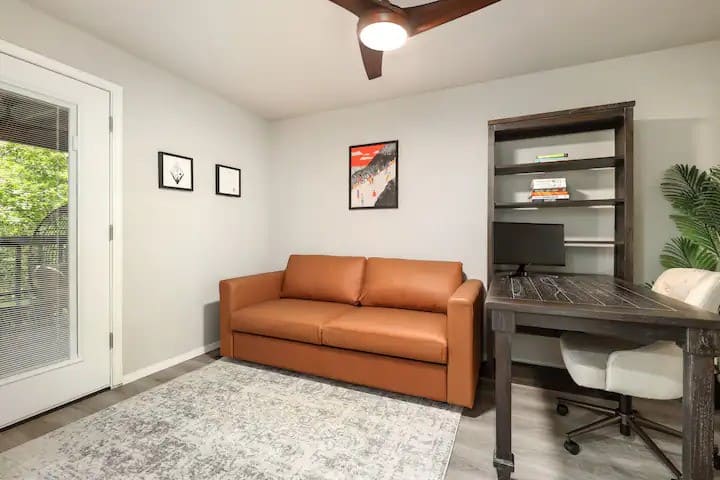 Bedroom office with queen size pullout couch, ceiling fan and full sized desk. Equipped with monitor with HDMI cord, accessible outlets and outlet with built in USB ports. 
