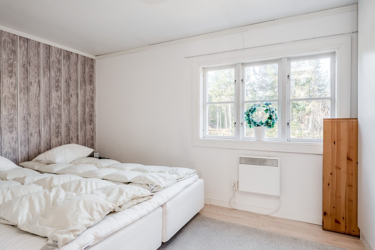 Sovrum intill vardagsrummet med dubbelsäng.