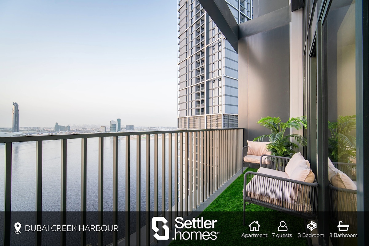 A private balcony offers sweeping views of the Creek and skyline. Comfortable seating is provided, surrounded by greenery. The railing is designed with vertical slats, allowing for unobstructed vistas while ensuring safety. Natural light brightens the space, enhancing the tranquil ambiance.
