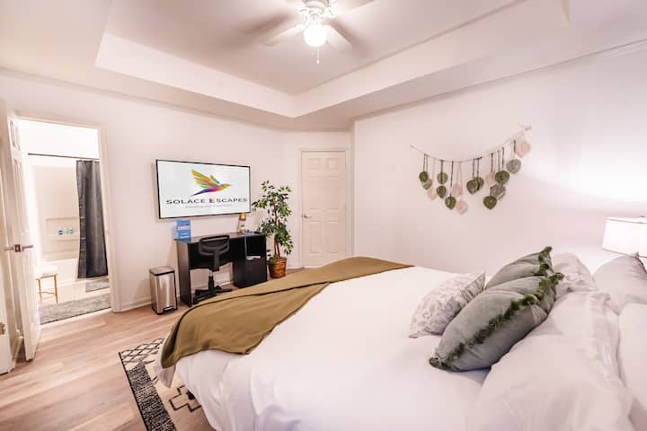 Priestranná spálňa s manželskou posteľou King, pracovným stolom, plyšovou kolieskovou stoličkou, zlatou lampou a 55-palcovou HD televízorom s plochou obrazovkou. Klenuté stropy dodávajú scéne priestrannú útechu. 