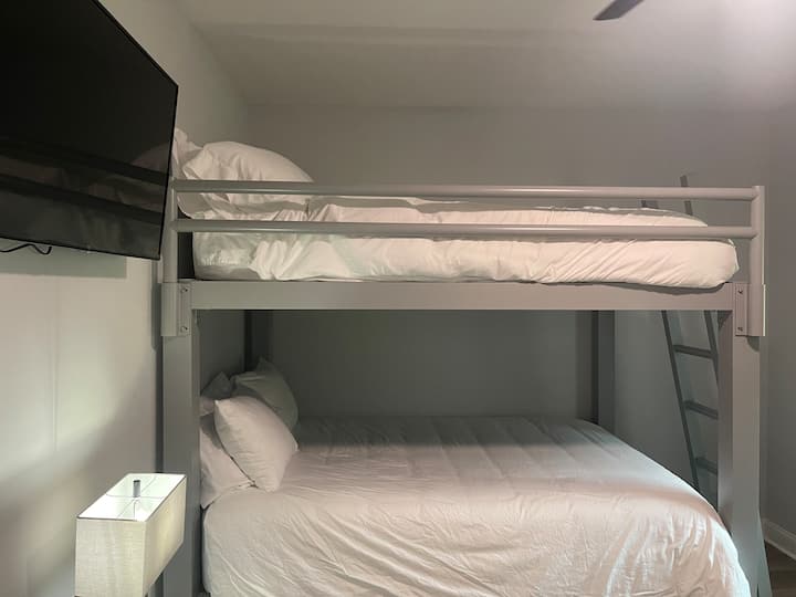 Literas para adultos con cama tamaño queen en la parte inferior y queen en la parte superior. Hay una cama nido de tamaño completo que se extiende