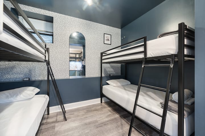 Pogled izbliza na spavaću sobu s krevetima na kat, zidom od tapeta s uzorkom i prozor s pogledom na ulicu.