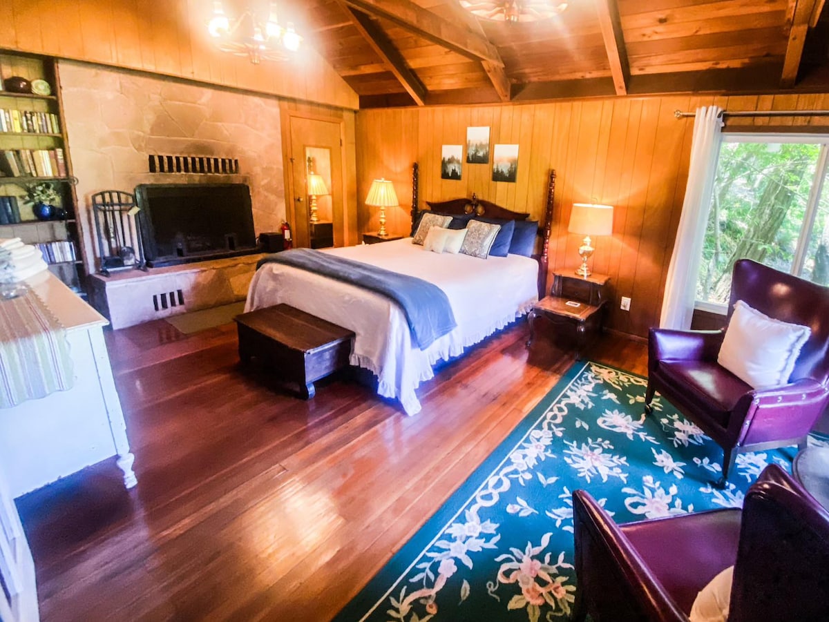 Grande chambre principale avec cheminée king size et coin salon avec vue sur la rivière