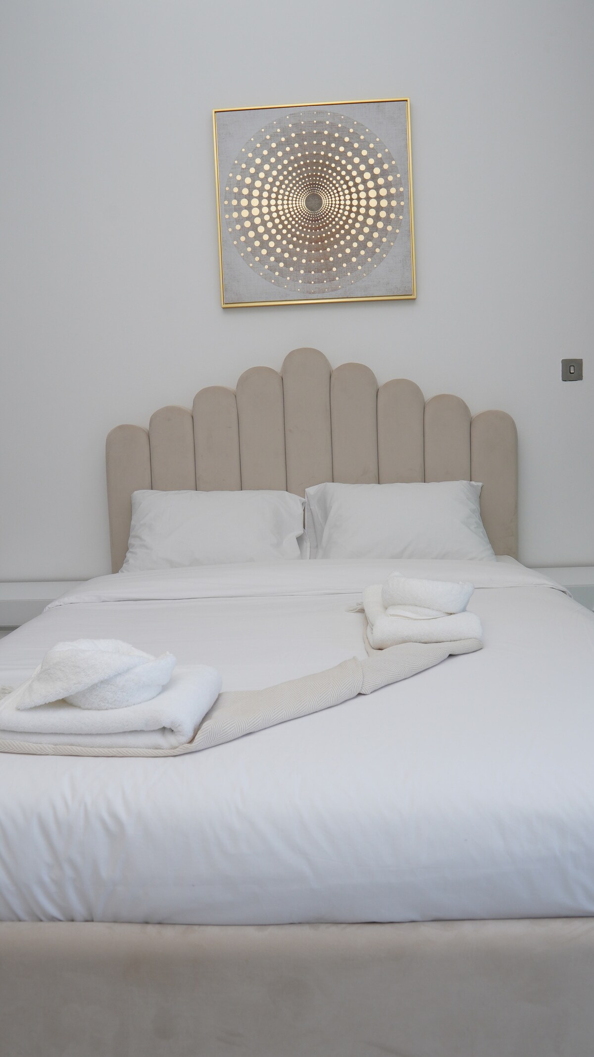 Dormitorio sereno con ropa de cama lujosa, iluminación suave y decoración refinada. Las grandes ventanas enmarcan hermosas vistas, creando un refugio tranquilo y aireado diseñado para la comodidad y la relajación.