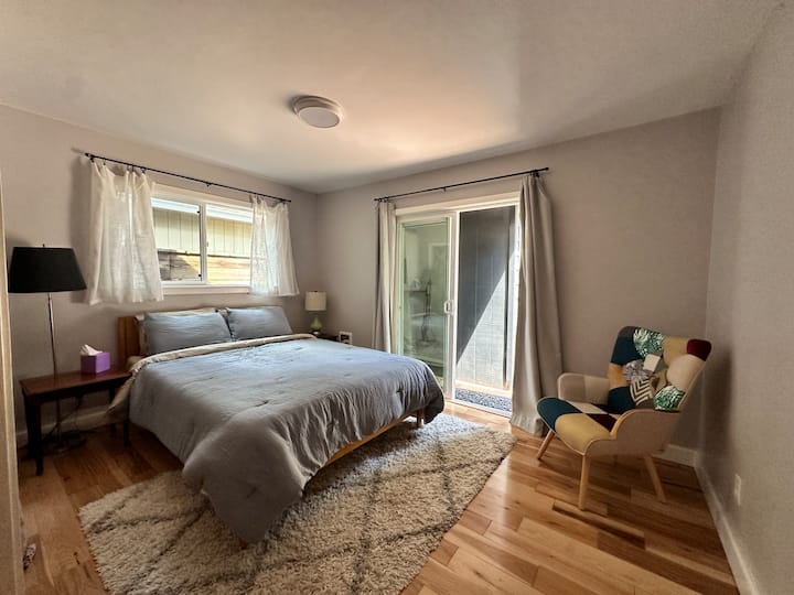 The main-level second bedroom features a queen-sized bed, a closet with built-in shelves, and storage. Enjoy private deck access and a full bathroom conveniently located next door for added comfort.