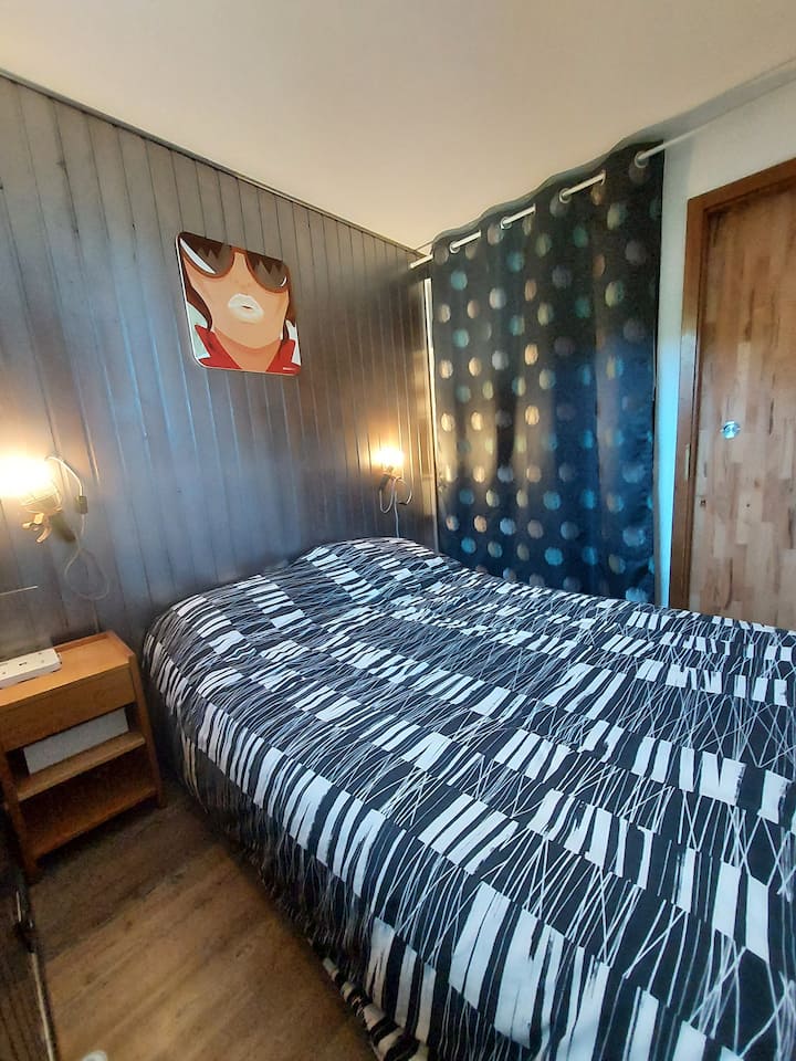 Naast de keuken is de eerste slaapkamer bereikbaar via een schuifdeur. Er is een tweepersoonsbed, lakens en kussens, evenals opbergruimte voor je kleding. 