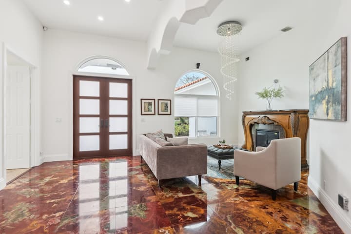 Step into a bright, elegant living room with soaring ceilings, onyx floors, and electric fireplace that adds warmth and charm. Relax in the cozy seating area overlooking the lush front yard. The comfortable atmosphere makes you feel right at home.