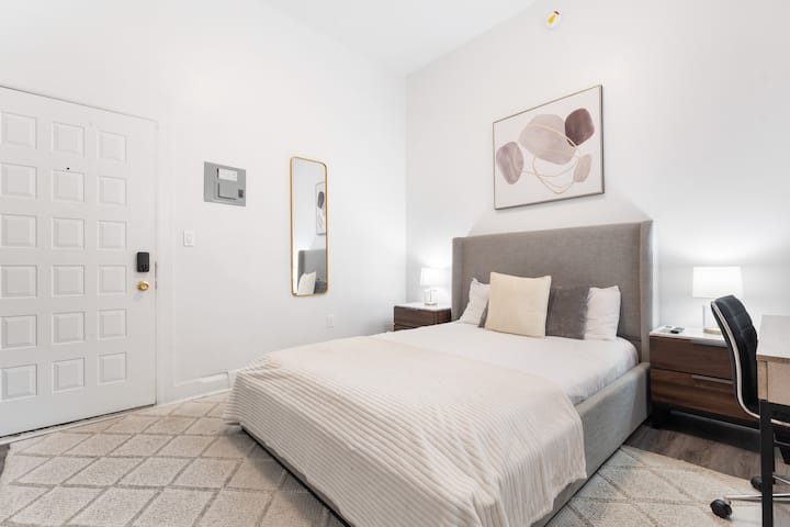 Útulná spálňa s manželskou posteľou, ideálna na pokojný pobyt. Zrkadlo na stene dodáva miestnosti hĺbku a svetlo, zatiaľ čo malý písací stôl poskytuje praktický priestor na prácu alebo osobné úlohy.