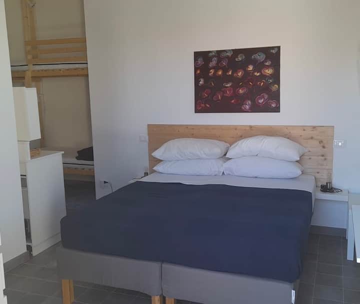 Chumba cha watu wawili kilicho na kitanda cha ghorofa. Bafu la chumbani lenye starehe zote (bidhaa za bafu, mashine ya kukausha nywele ya umeme, bafu na dirisha), jiko dogo lenye sahani ya kuingiza na baa ndogo, bafu la nje lenye bustani ya kujitegemea!