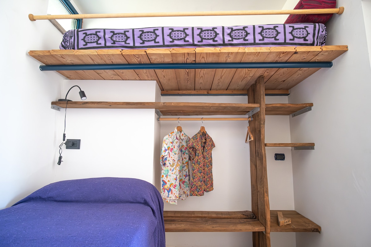 Dhomë dopio, pa derë, me krevat marinari dhe dollap druri me arra të ekspozuara.