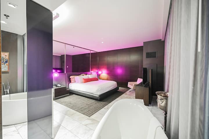 Dormitorio con bañera independiente e iluminación púrpura