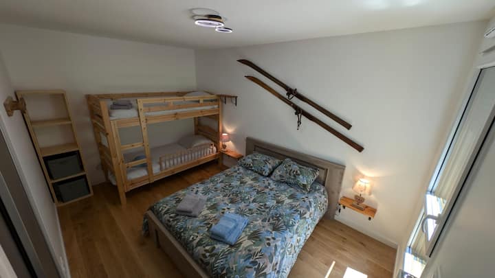 Bedroom with double bed and bunk bed, closet and column.
