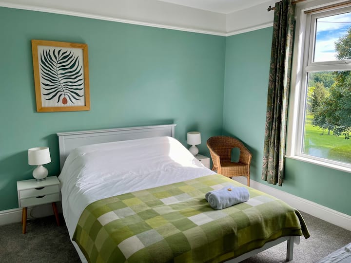 De grote slaapkamer met een kingsize bed met uitzicht op het park vanuit het raam. 