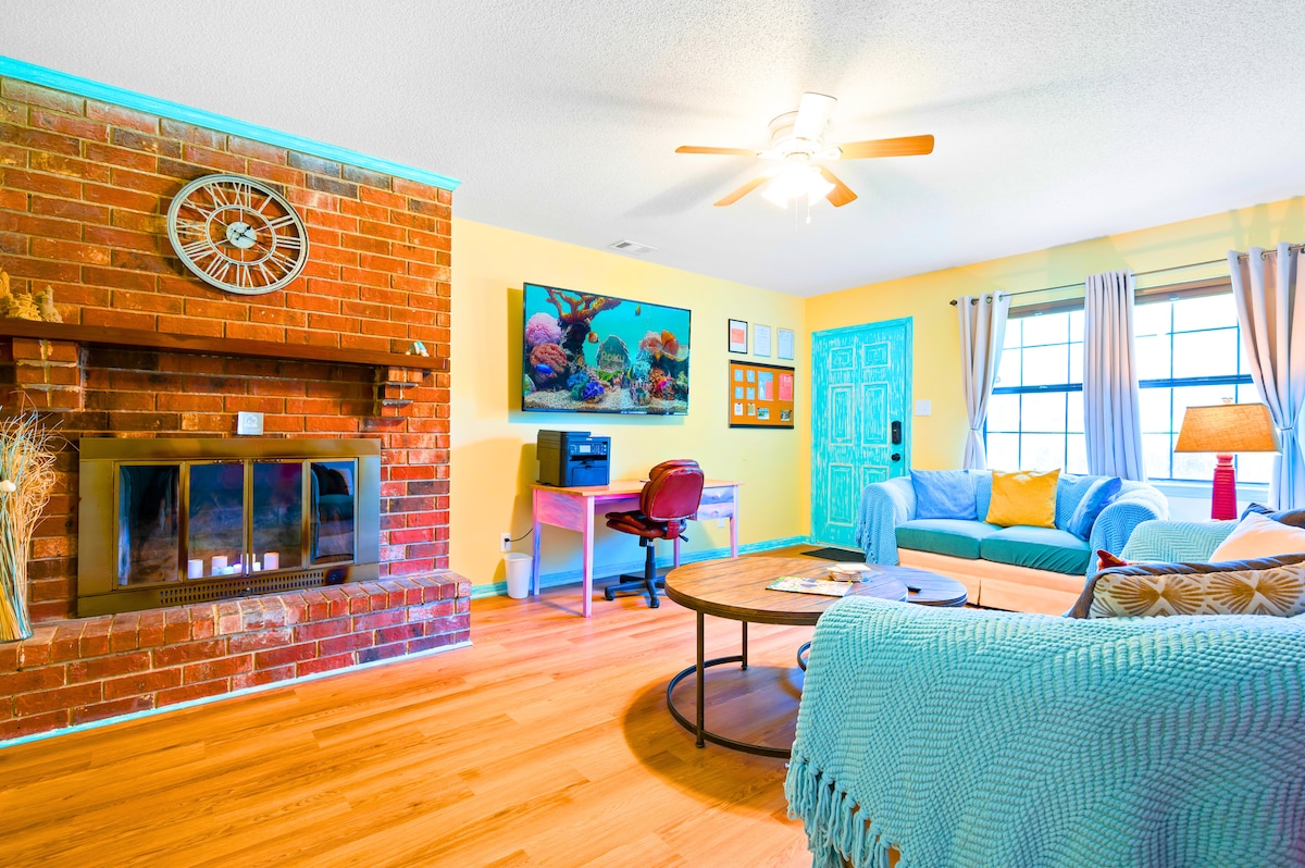 Doživite živahnost ovog prostranog dnevnog boravka. Svijetle boje, plišani jastuci i morski pjeni zeleni detalji pozivaju na opuštanje. Uživajte u pametnom 4K televizoru od 65", udobnoj radnoj stanici i muralu s ljuljačkom na španjolskoj mahovini. Savršeno za opuštanje i avanturu!