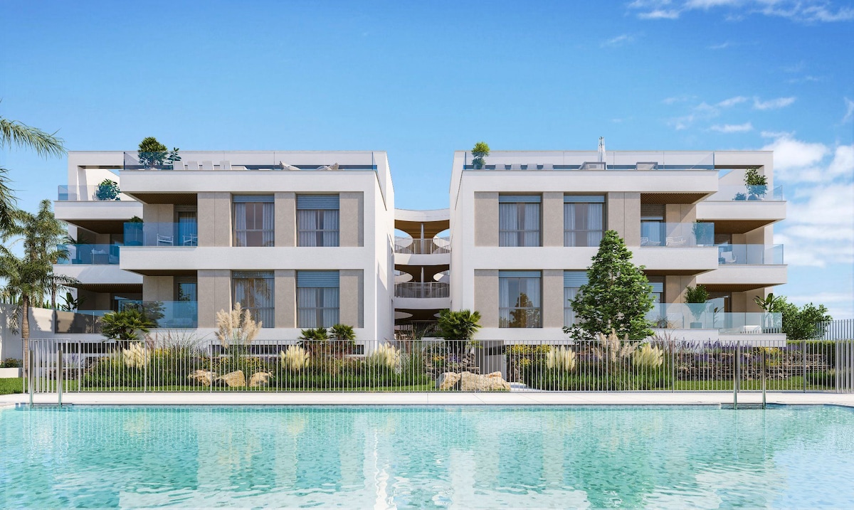 A modern two-story apartment building is presented, featuring multiple balconies and large glass windows. Lush landscaping surrounds the property, and a sparkling swimming pool reflects the blue sky, enhancing the serene atmosphere of the environment.