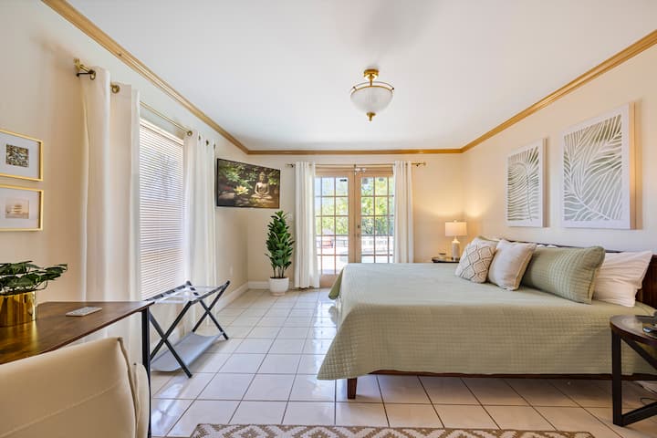 Second Master suite features King size bed, TV, French doors providing direct access to the pool and river views, ample work desk, and en-suite bath with walk-in closet.
