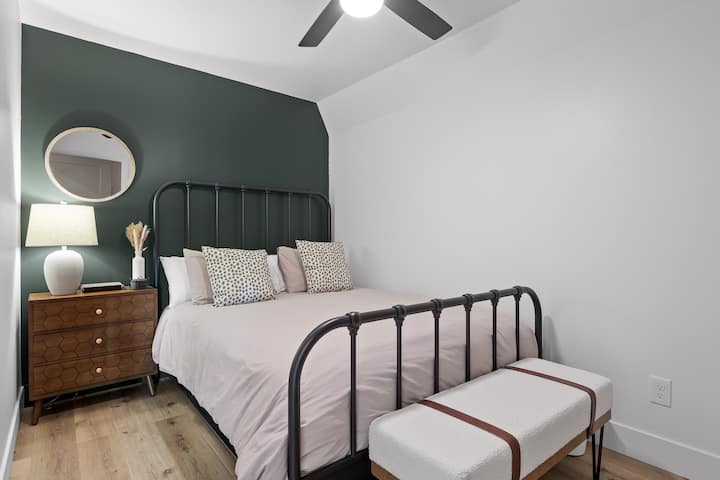 Very comfortable queen size bed with extra pillows, a night stand, lamp and a sitting bench.