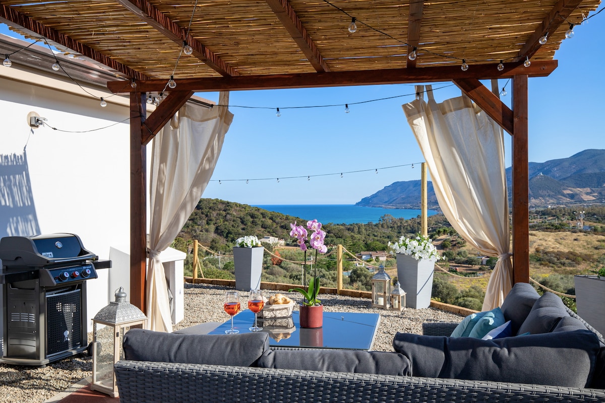 An outdoor gazebo offers a cozy lounge area with a comfortable seating arrangement, complemented by a table with refreshments. Potted plants and scenic mountain views create a tranquil atmosphere, while string lights add a soft illumination for evening relaxation.