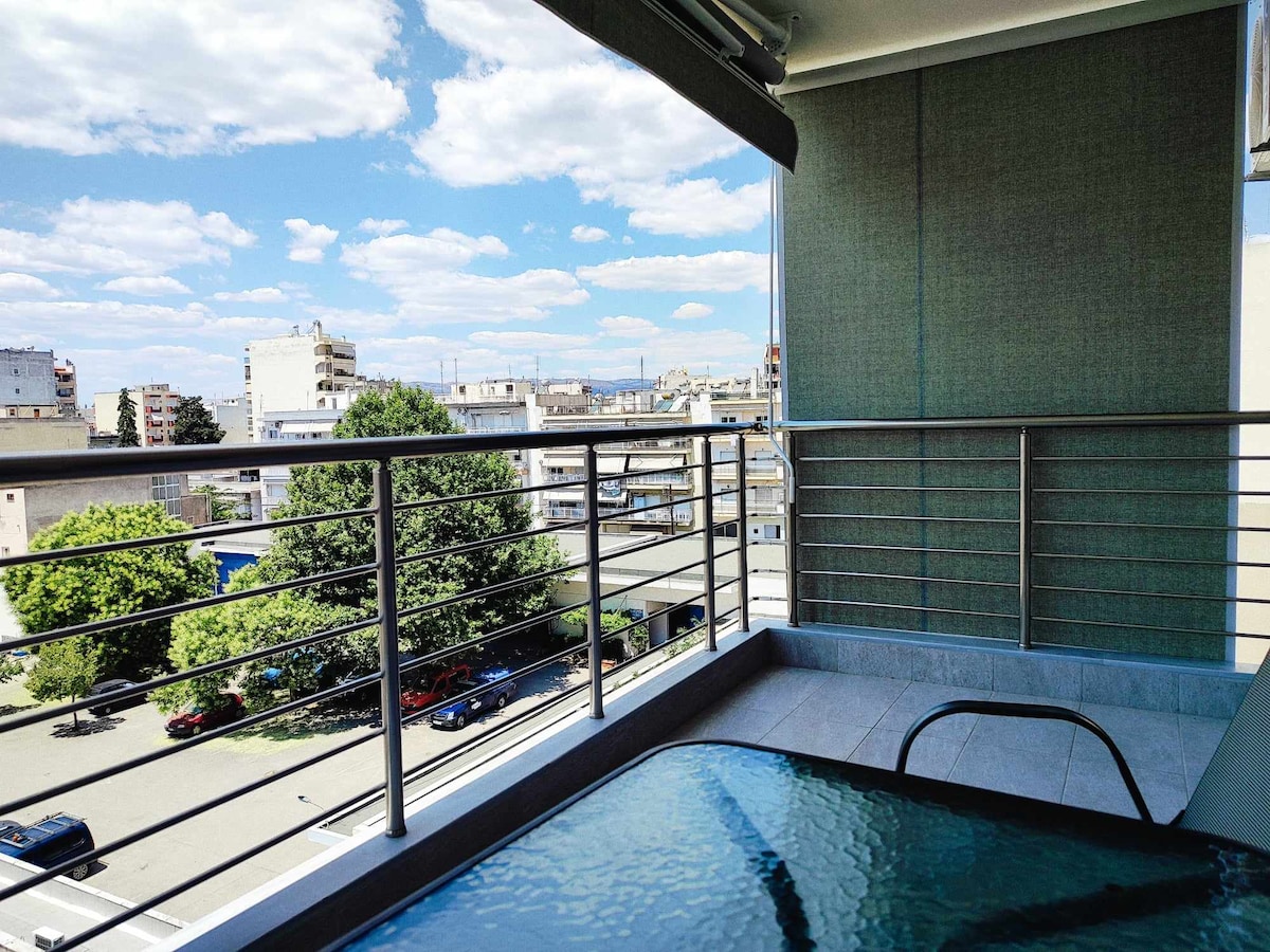 A balcony view reveals a clear blue sky dotted with clouds, overlooking a tree-lined street. The modern railing enhances the open feel of the space, while a glass table sits on the balcony, providing a space for relaxation.