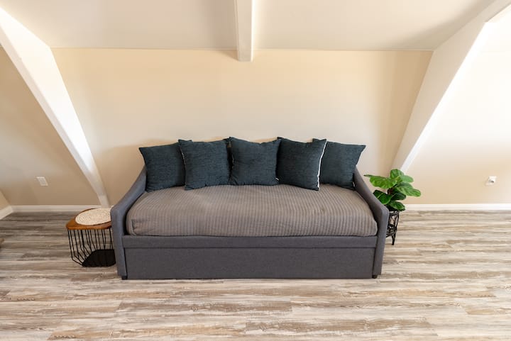 Удобно сместено во поткровјето на River Road Retreat, со стилски дневен кревет со тркалце кое е совршено за дополнителни гости или простор за опуштање.