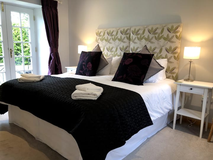 Master bedroom with super king-sized bed and french-doors to gardens.